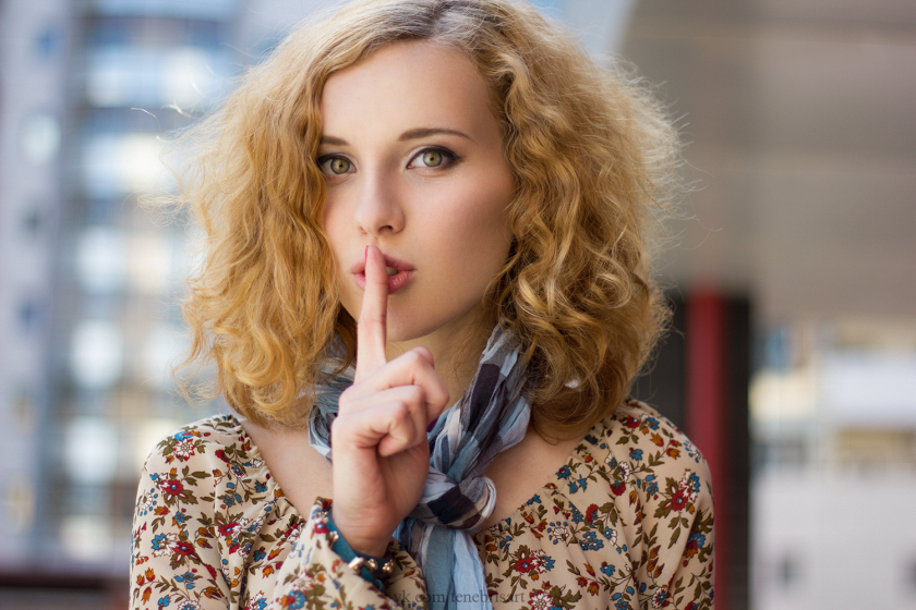 Lady making shushing gesture holding finger up to lips