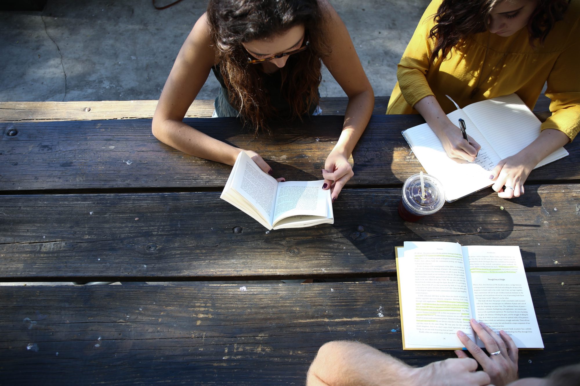 3 people studying at an outside bench