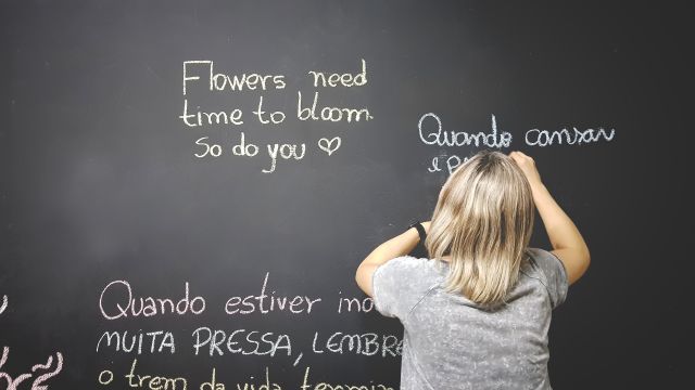 Child writing motivational quotes on a blackboard