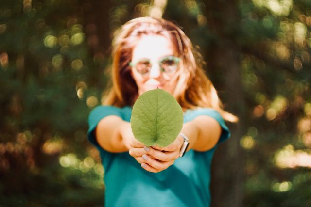 Woman holding leaf up to camera