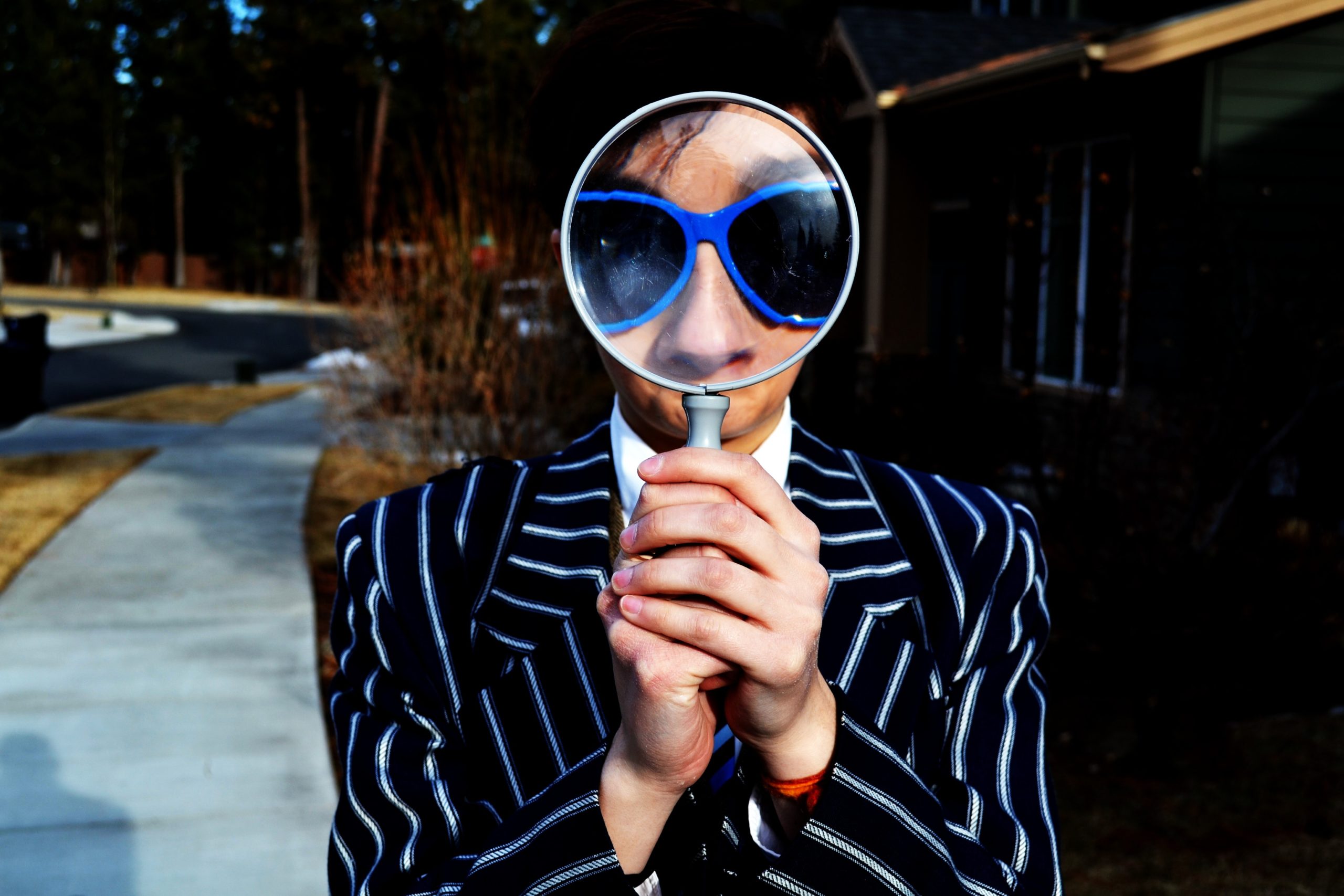 Man in a suit holding magnifying glass up to his face