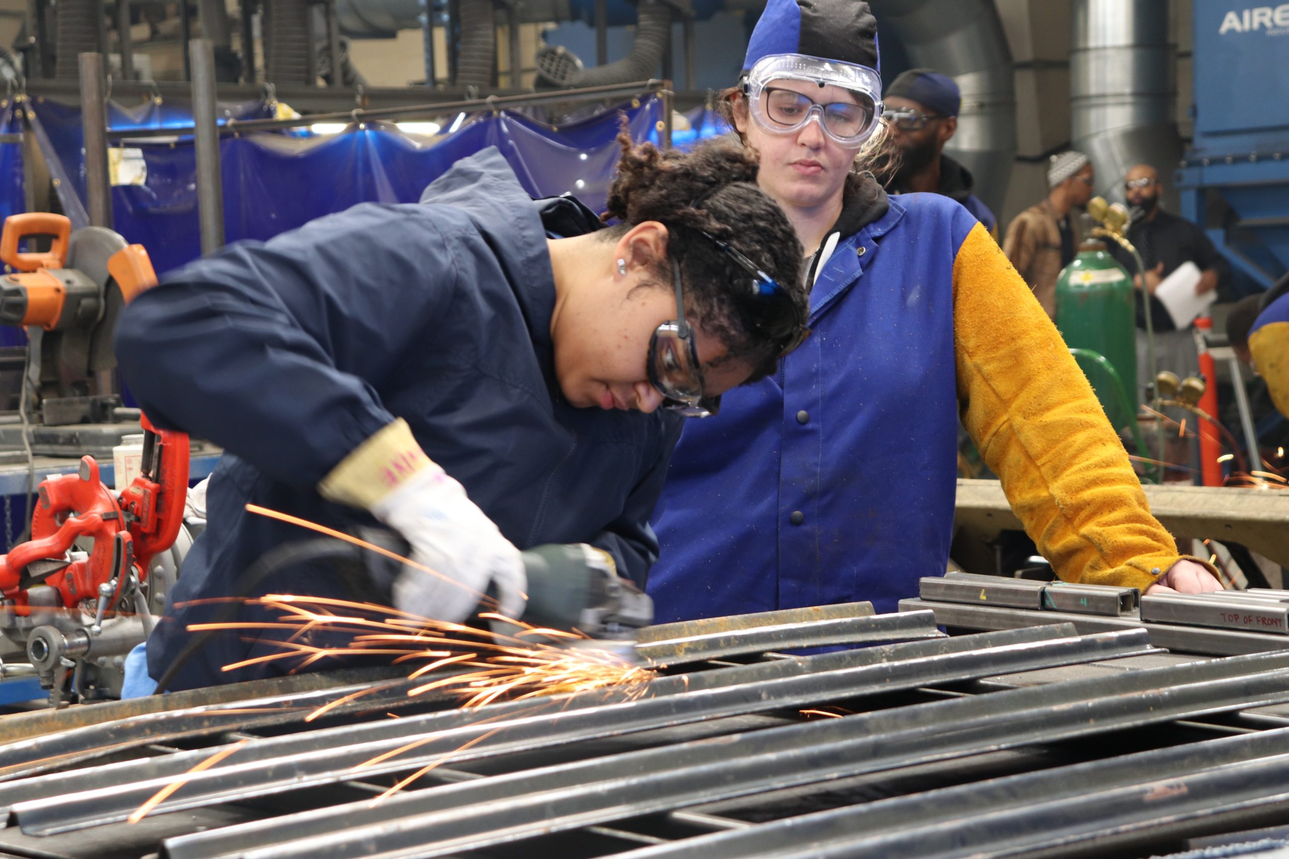 Two women soldering in mechanical workshop