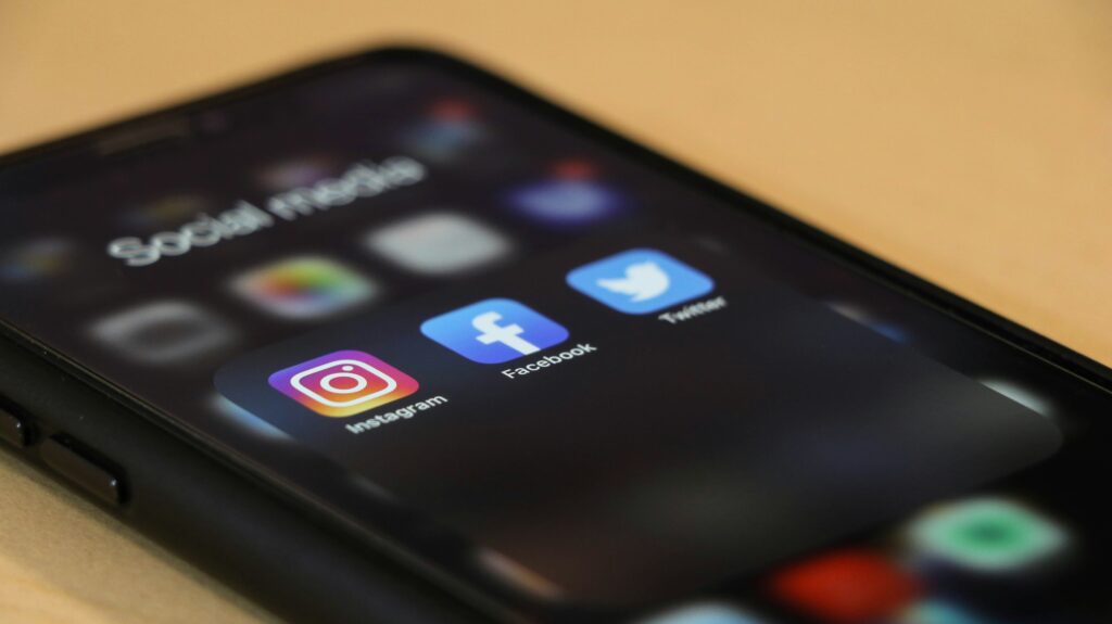 A smartphone lying on a surface. The screen is unlocked and the Instagram, Facebook and Twitter logos are visible.
