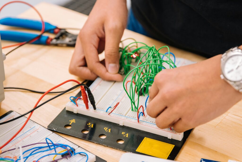 Hands attaching green, red and blue wires into a motherboard.